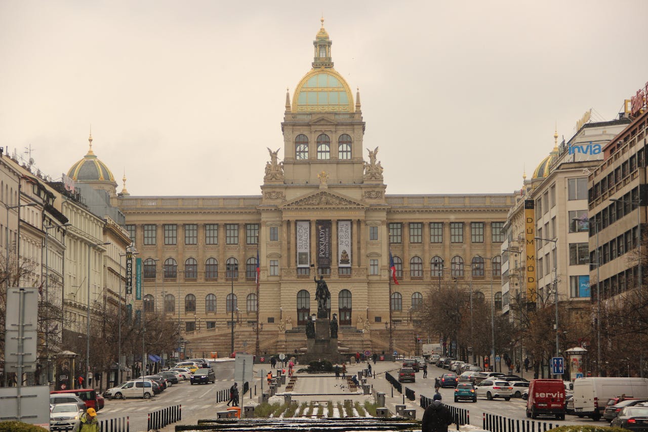 Street view of the National Museum in Prague on an overcast day, capturing urban life.